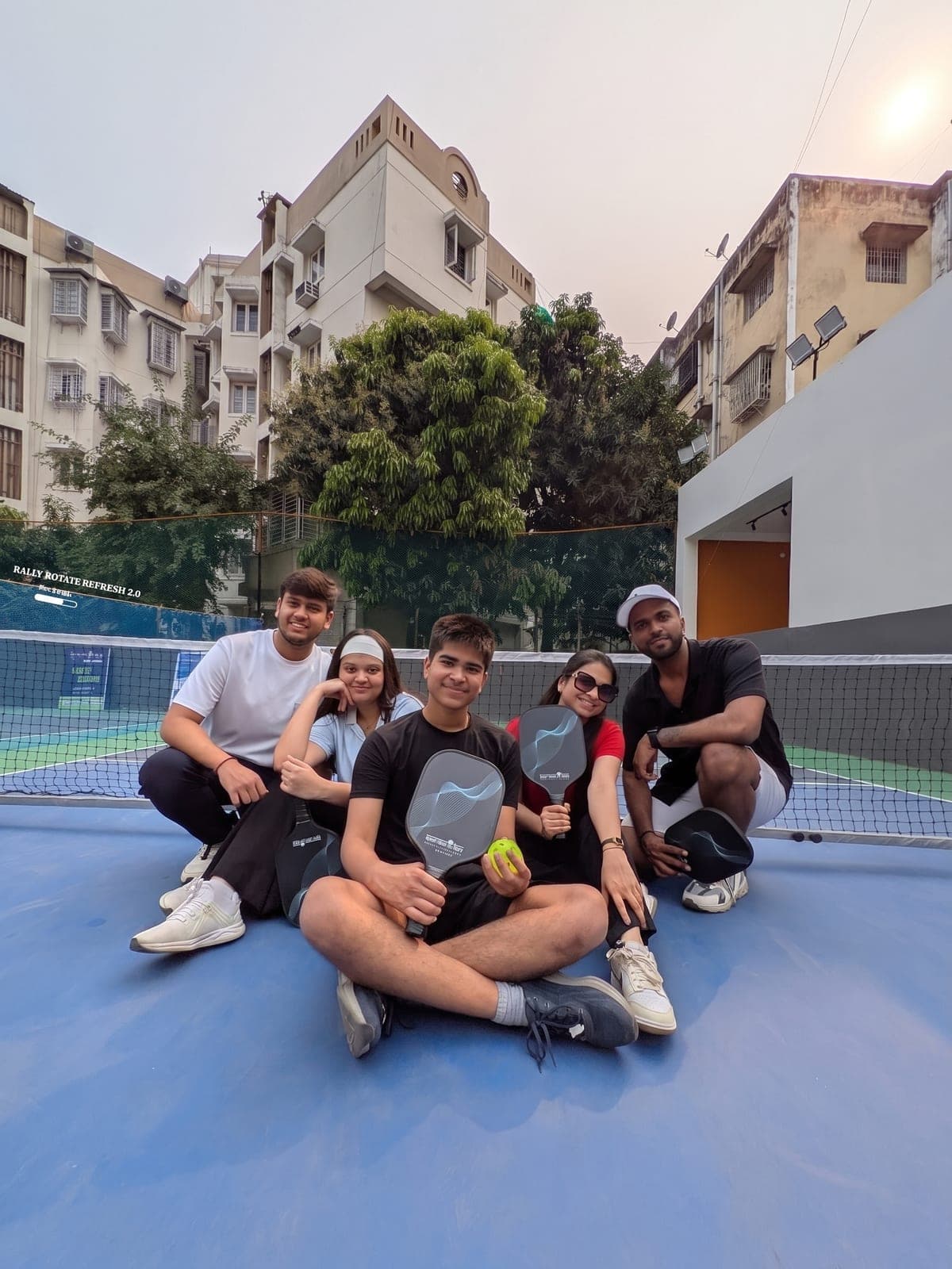Friends courtside at dusk with their paddles
